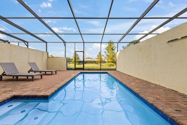Una piscina con una vista despejada del cielo y un camino de ladrillo.
