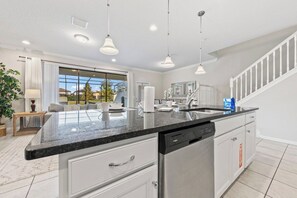 A modern kitchen with a large island, white cabinetry, and a dishwasher.