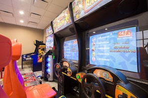 Um salão de jogos de corrida com várias telas exibindo jogos de corrida e um volante.