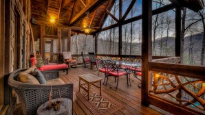 A wooden deck with outdoor seating, a fireplace, and a view of the surrounding forest. - Winding Log Ridge- Pet Friendly | Screened Porch | 11 miles from Downtown (Blue Ridge)