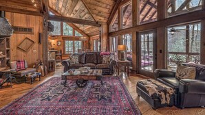 A spacious living room with a large rug, leather sofas, and a fireplace. - Winding Log Ridge- Pet Friendly | Screened Porch | 11 miles from Downtown (Blue Ridge)