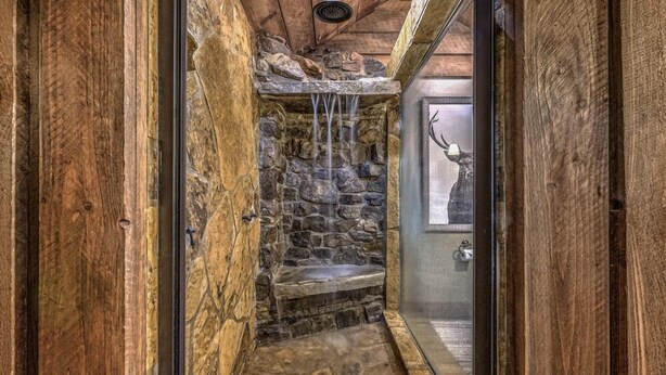 A stone shower with a waterfall feature, wooden walls, and a deer head decoration. - Winding Log Ridge- Pet Friendly | Screened Porch | 11 miles from Downtown (Blue Ridge)