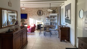 Una sala acogedora con una pared de piedra, una mesa de comedor de madera y una estantería.