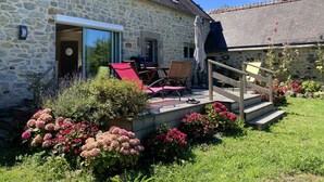 Una casa de piedra con un patio, mobiliario exterior y un jardín lleno de flores.