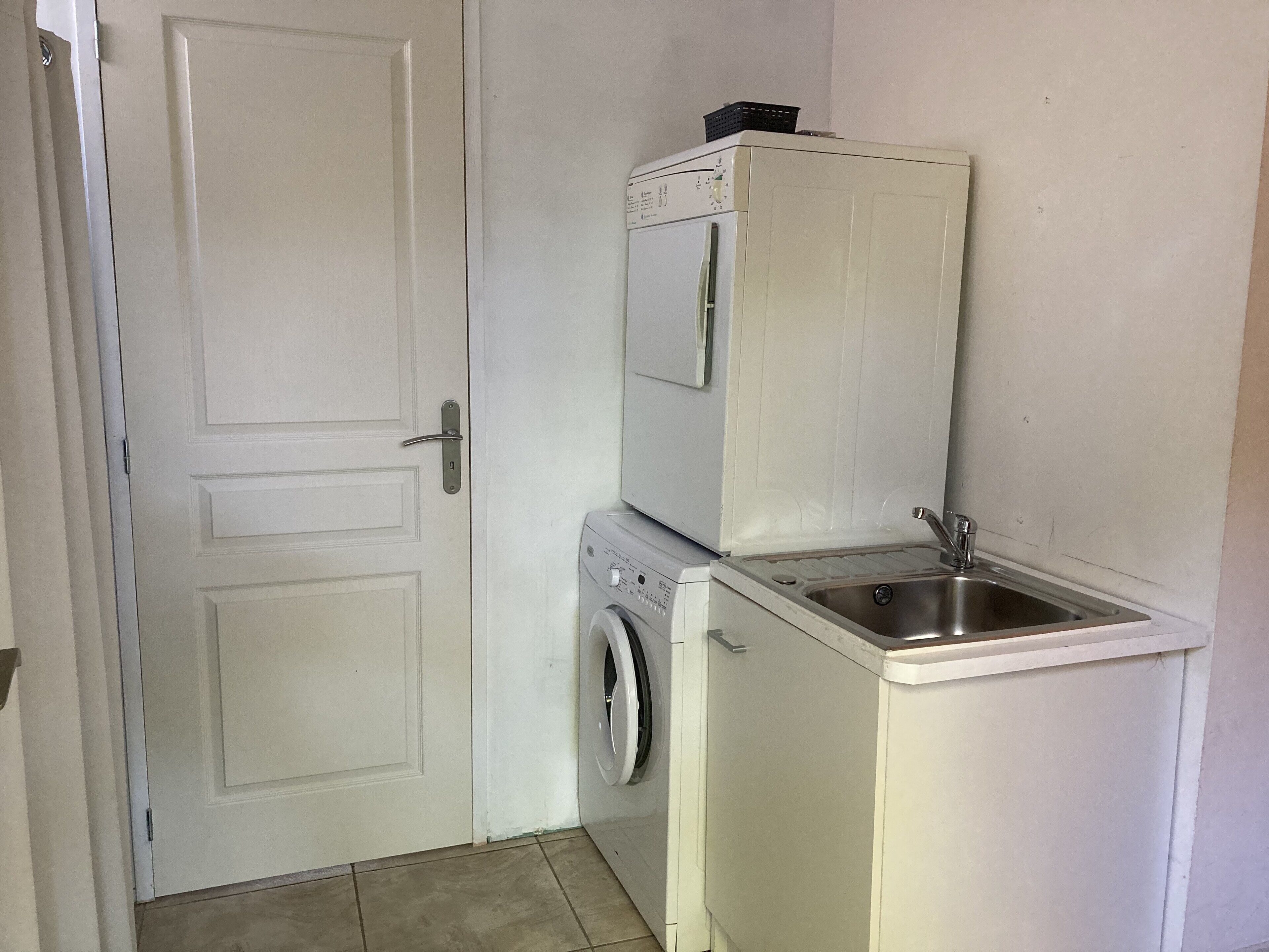 Un espace buanderie compact comprenant un lave-linge et un petit évier.