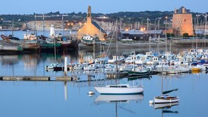 Un puerto deportivo con barcos amarrados, un faro y una torre histórica.