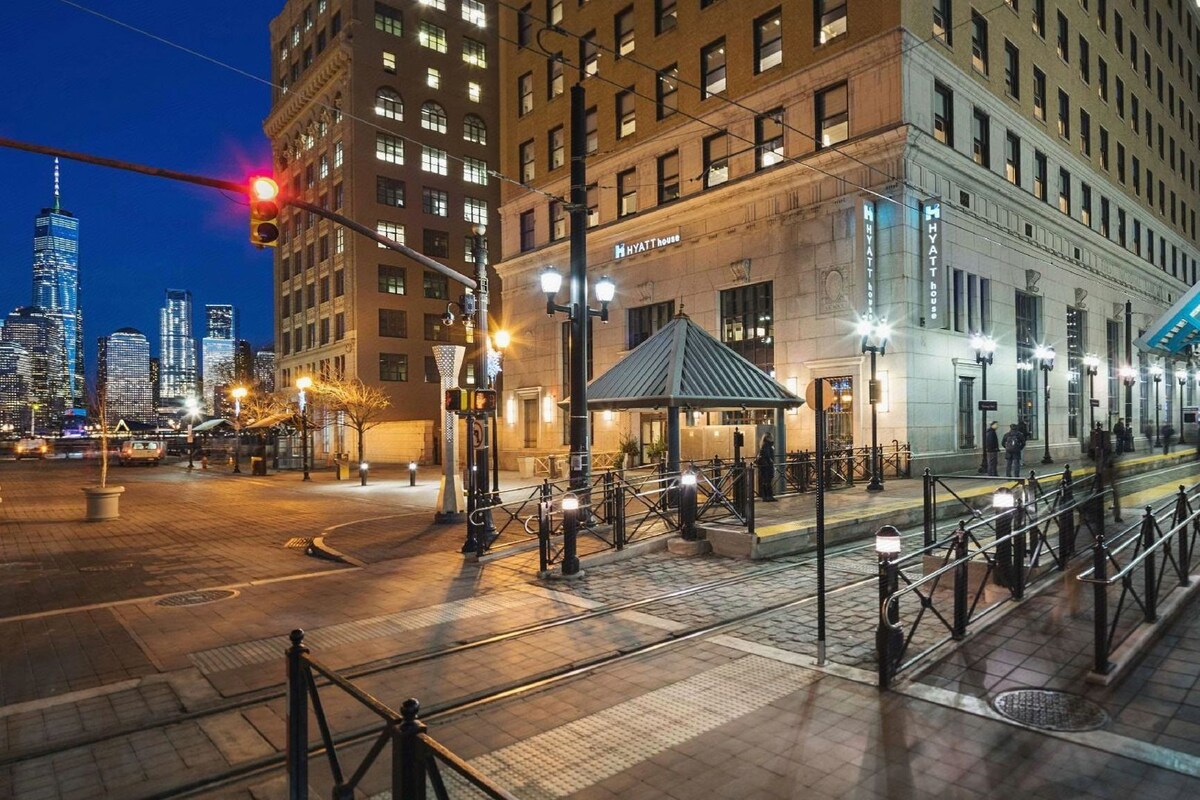 A hotel with a classic architectural style, a covered entrance, and a view of the city skyline.