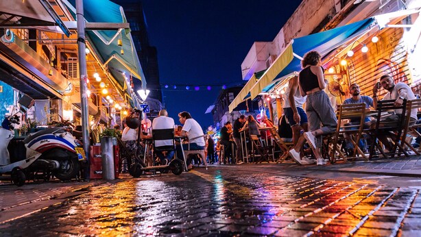 A bustling street market at night with people walking and sitting at tables. - Beta Studios ApartHotel (Tel Aviv)
