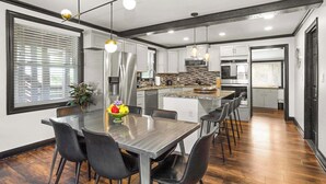 Une cuisine moderne dotée d’appareils électroménagers en acier inoxydable, d’un îlot central et de luminaires suspendus.