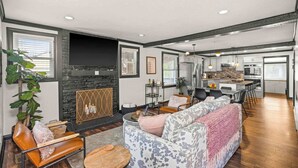 Un salon moderne avec une cheminée, un coin salon et une cuisine en arrière-plan.