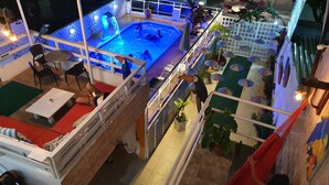 Uma área de piscina no terraço com um recurso aquático iluminado em azul, assentos externos e plantas em vasos.