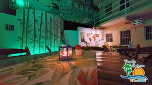 Um restaurante com um painel de bambu iluminado em verde, um mapa-múndi e uma mesa com um candeeiro.