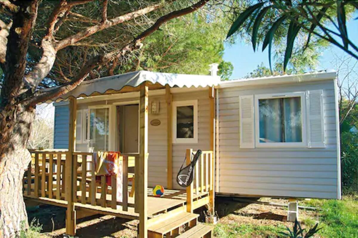 Une maison mobile avec une véranda, une raquette de tennis et un ballon de plage.