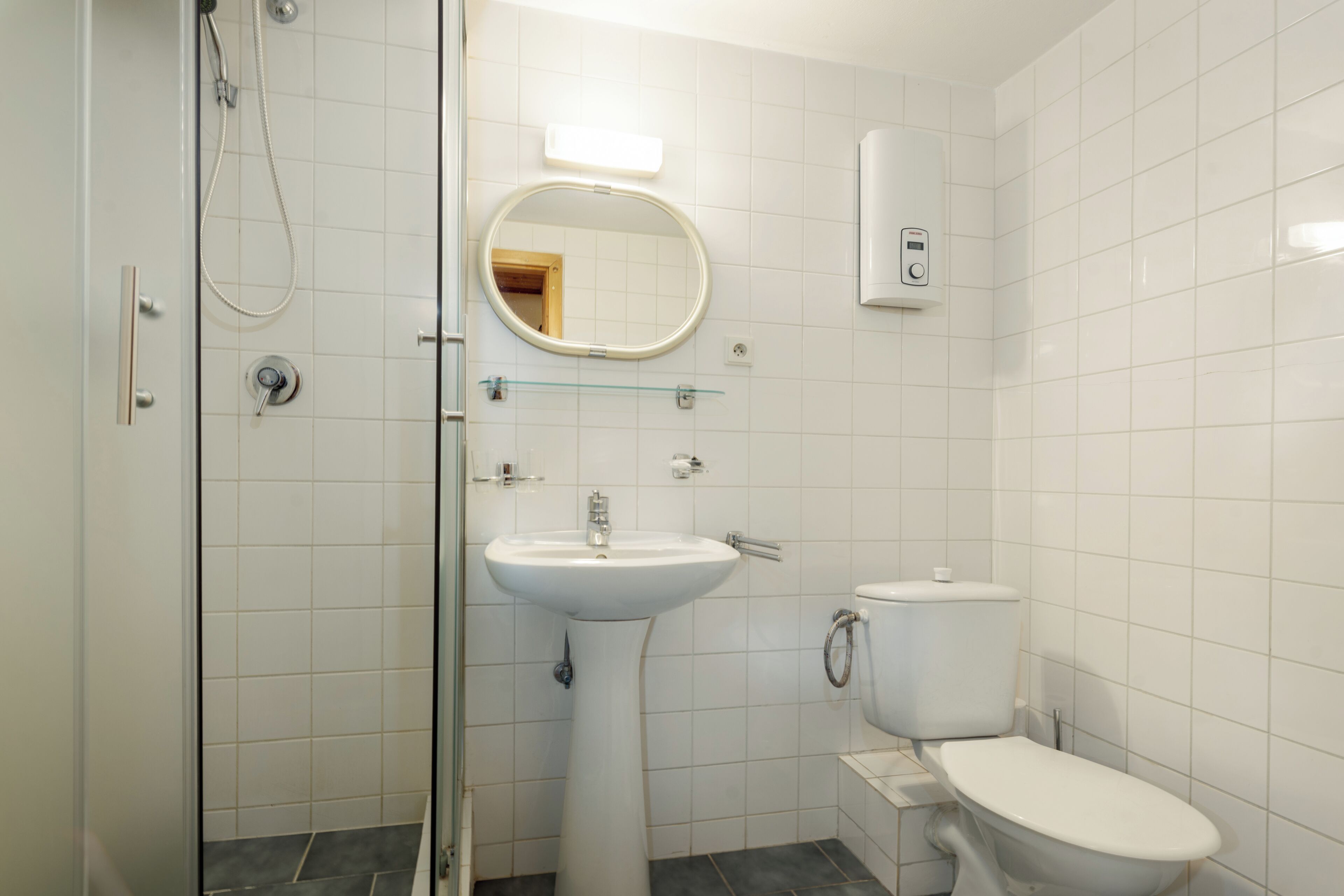 A bathroom with a shower, a sink, a toilet, and a mirror.