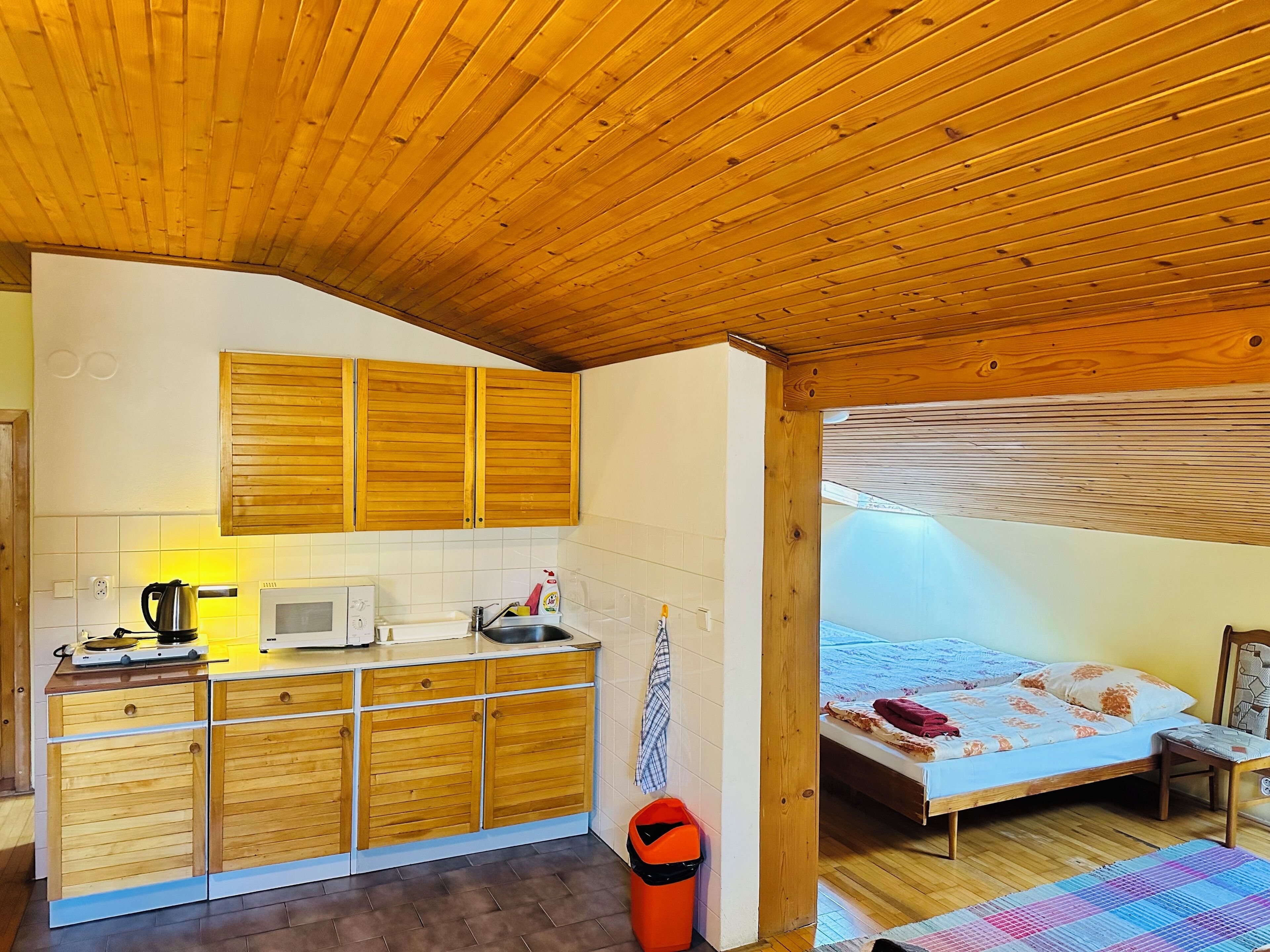 Quarto compacto com cozinha compacta, uma cama e teto de madeira.