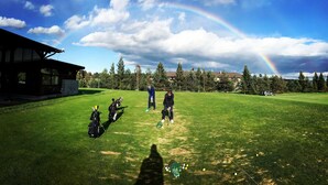 A golf course with a rainbow, a building, and trees in the background. - Penzion Pazicky (Stara Lesna)