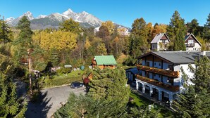A hotel with a large building, a parking area, and a mountainous backdrop. - Penzion Pazicky (Stara Lesna)