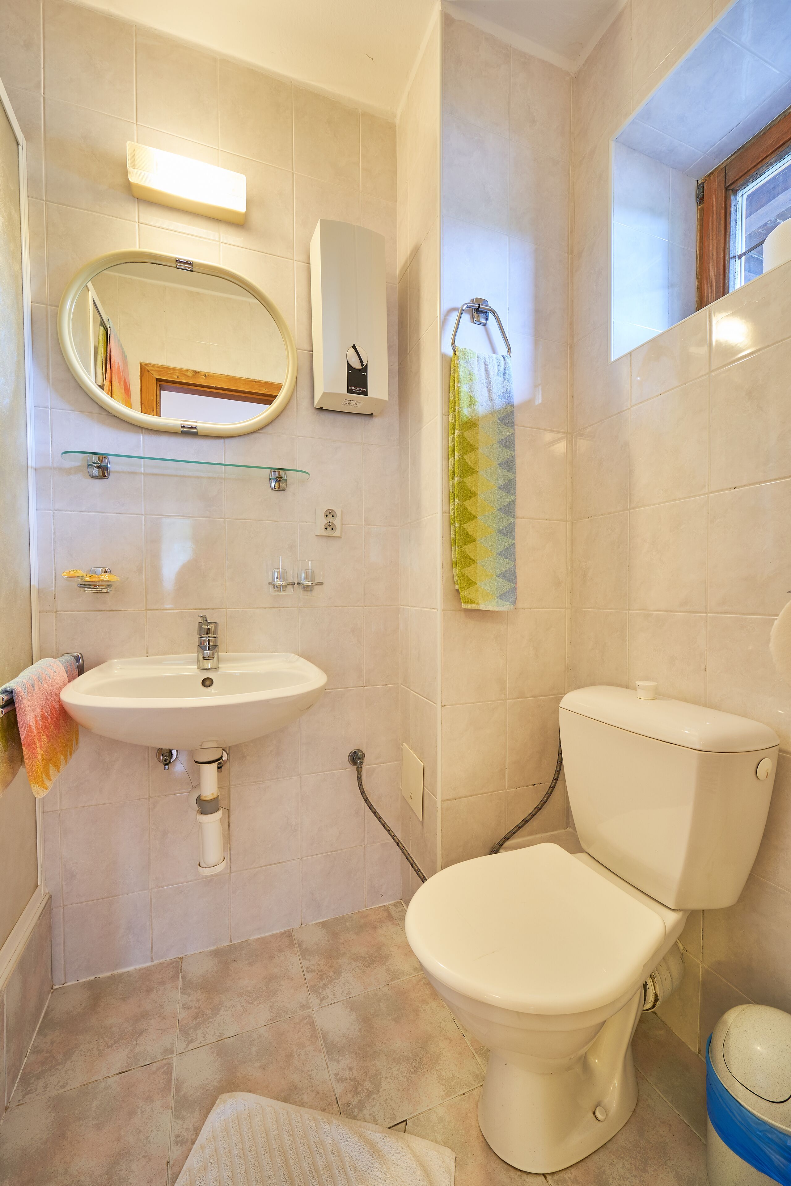 Une salle de bain équipée d’un lavabo, d’un miroir, de toilettes et d’un porte-serviettes.