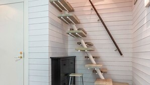 A corner of a room with a wooden staircase, a black cabinet, and a metal stool. - Teppolan rinne by Interhome (Salla)