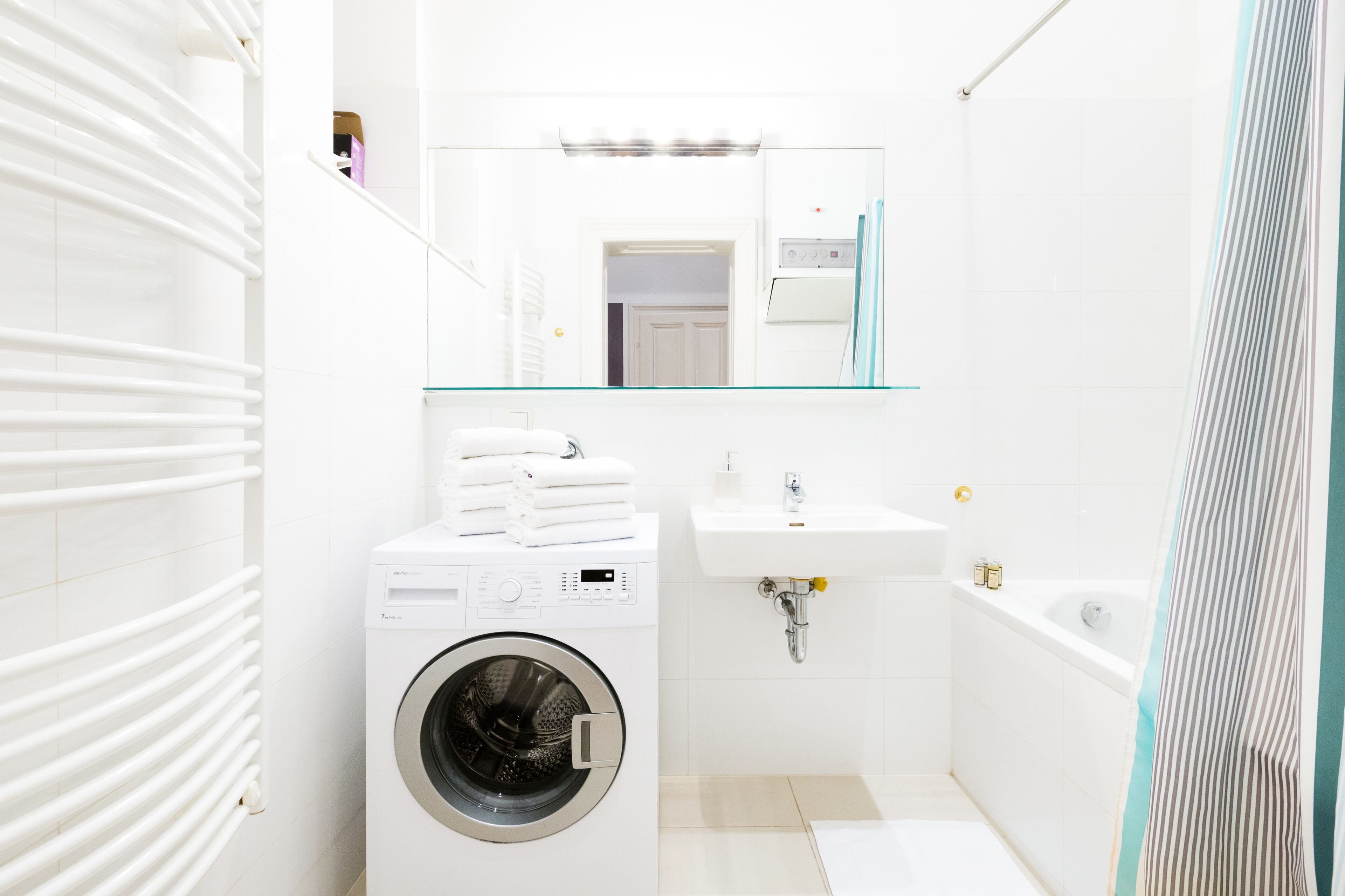 A modern bathroom with a washing machine, a sink, and a bathtub.