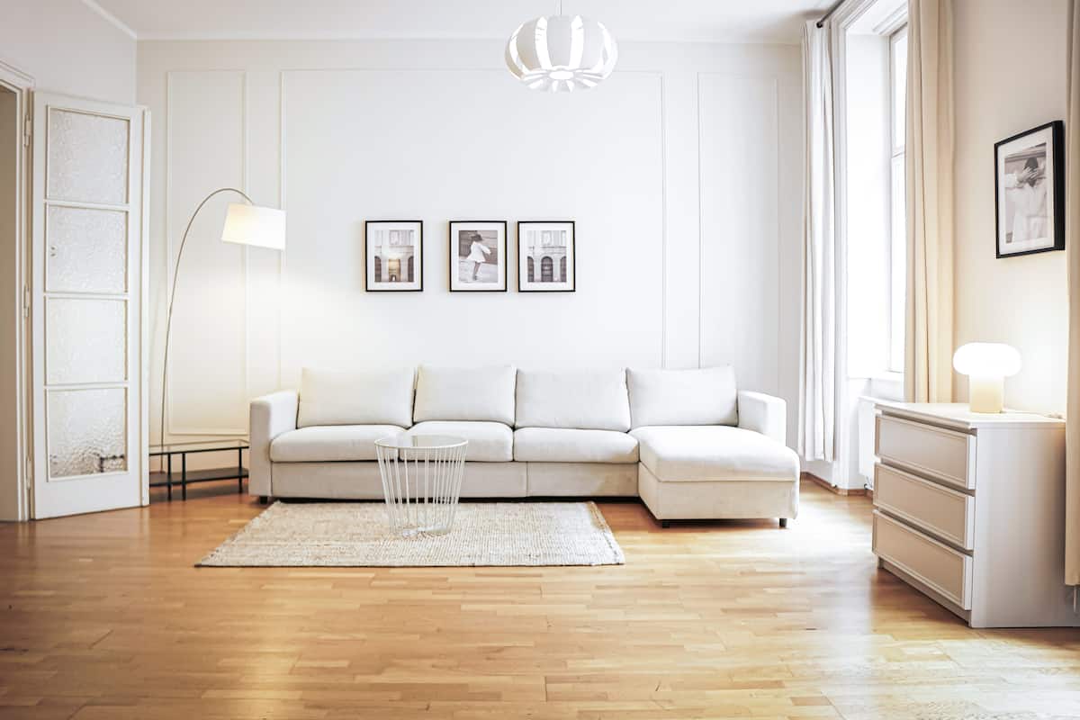 A modern living room with a white sofa, a floor lamp, and three framed pictures on the wall.