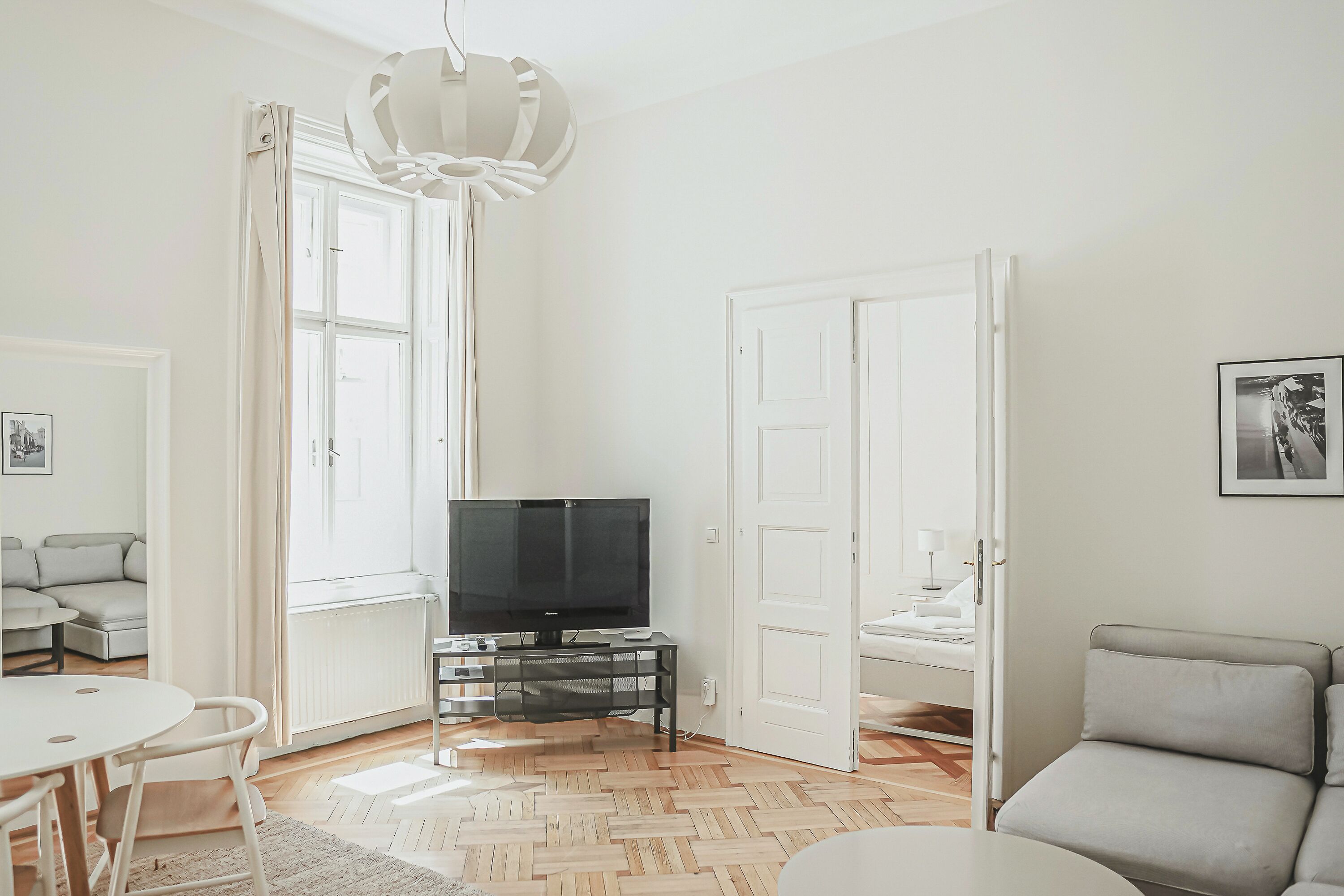 Una sala de estar moderna con televisor, un sofá, una mesa de comedor y una silla.