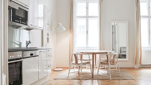 Eine moderne Küche mit weißen Schränken, einem Backofen und einer Mikrowelle. Es gibt einen Essbereich mit einem runden Tisch und vier Stühlen.