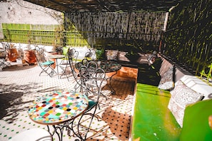 Un patio al aire libre con una mesa de mosaico, sillas de metal y un sofá verde.