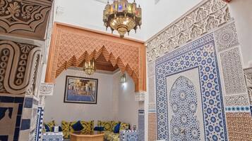 A room with a patterned floor, a seating area with cushions, and a decorative ceiling.