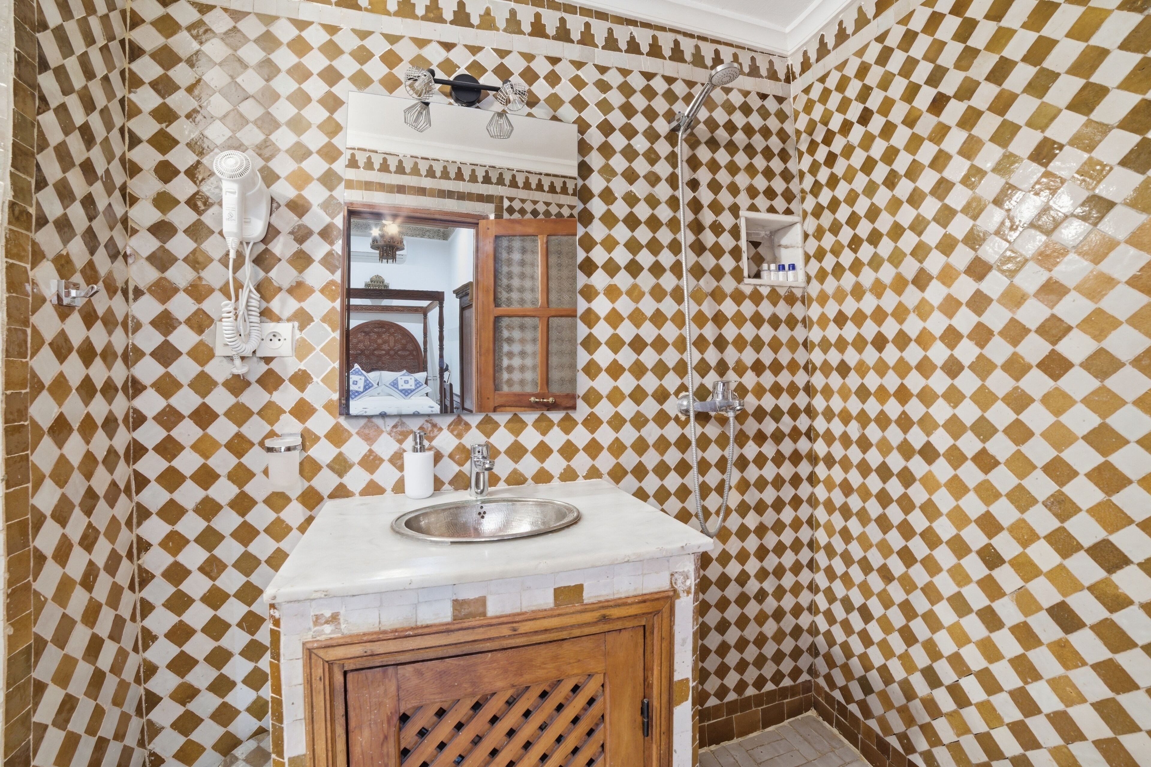 Un baño con suelo de baldosas a cuadros, un lavabo, un espejo y una ducha.