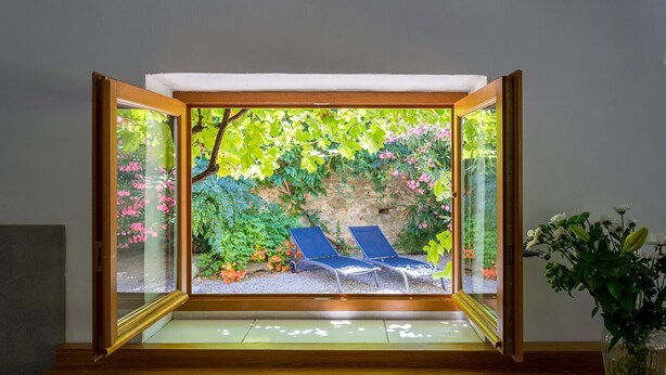 Una habitación con cerramiento de vidrio, dos sillones azules y una planta en maceta.
