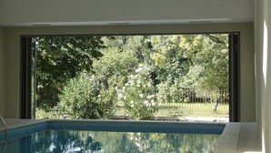 Piscina con tragaluces y vistas a árboles y una cerca.