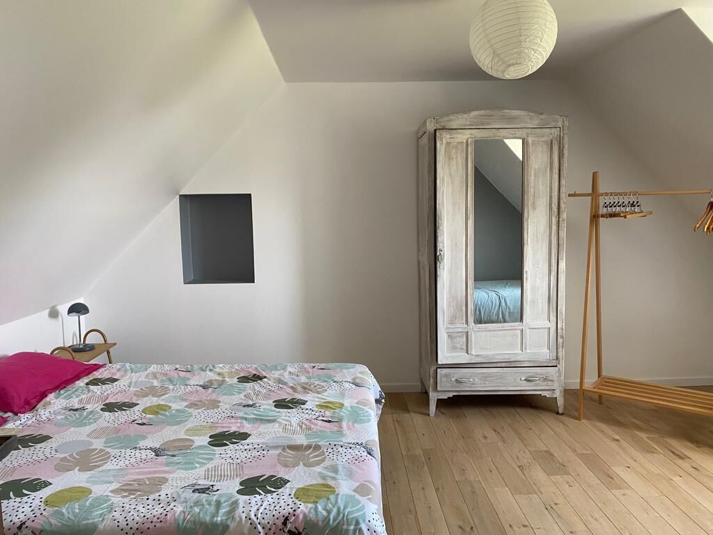 A bedroom with a bed, a wardrobe, and a hanging rack.