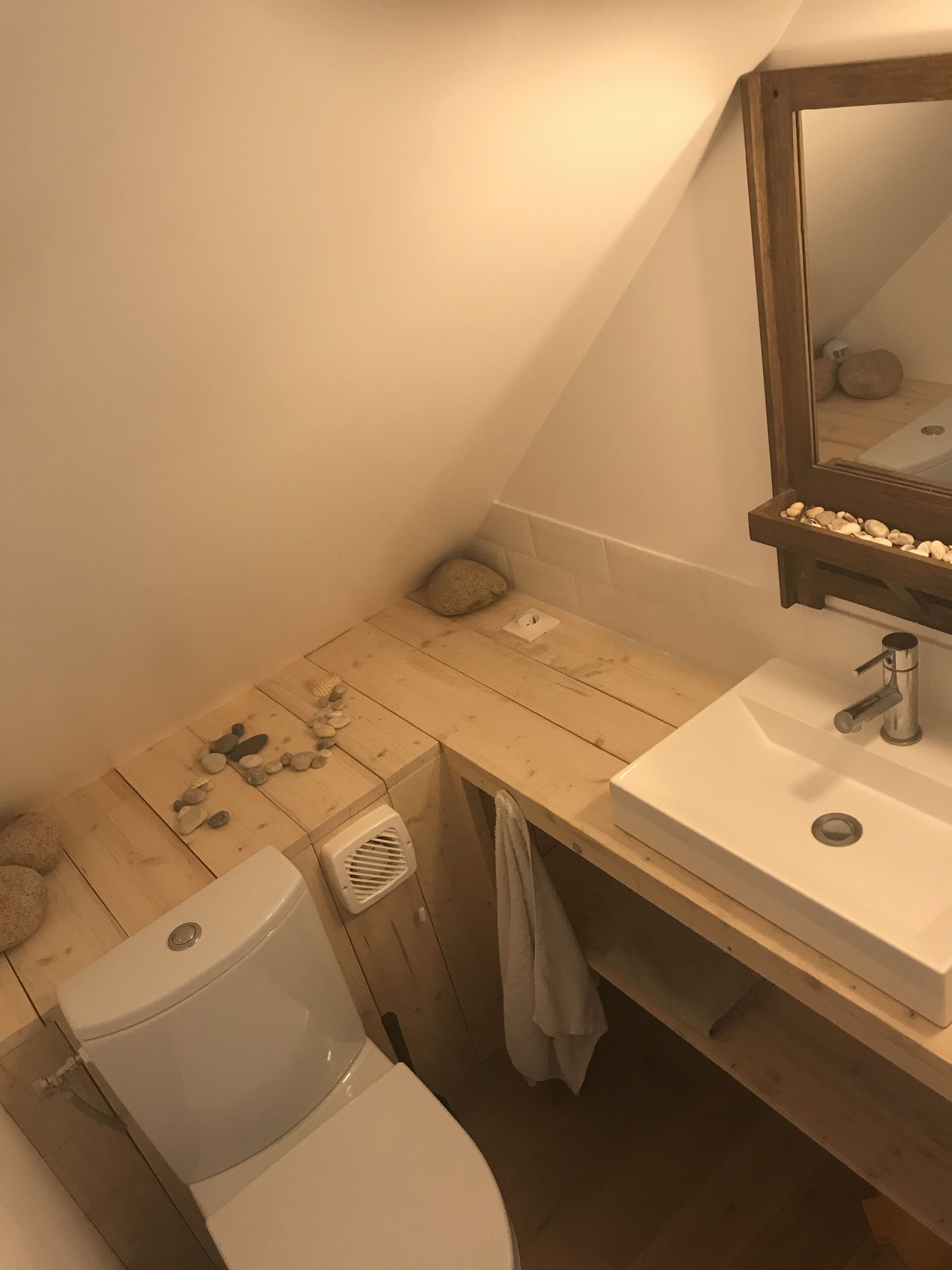 A bathroom with a wooden vanity, a white sink, a mirror, and a toilet.