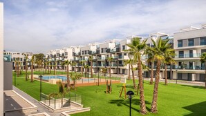 Een modern hotel met meerdere balkons, een zwembad en verzorgde groene gazons.