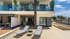 Een modern woongebouw met twee verdiepingen, een balkon, een terras en uitzicht op de omgeving.