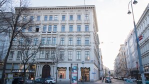 Un edificio histórico de varias plantas, con amplios ventanales y una entrada destacada.