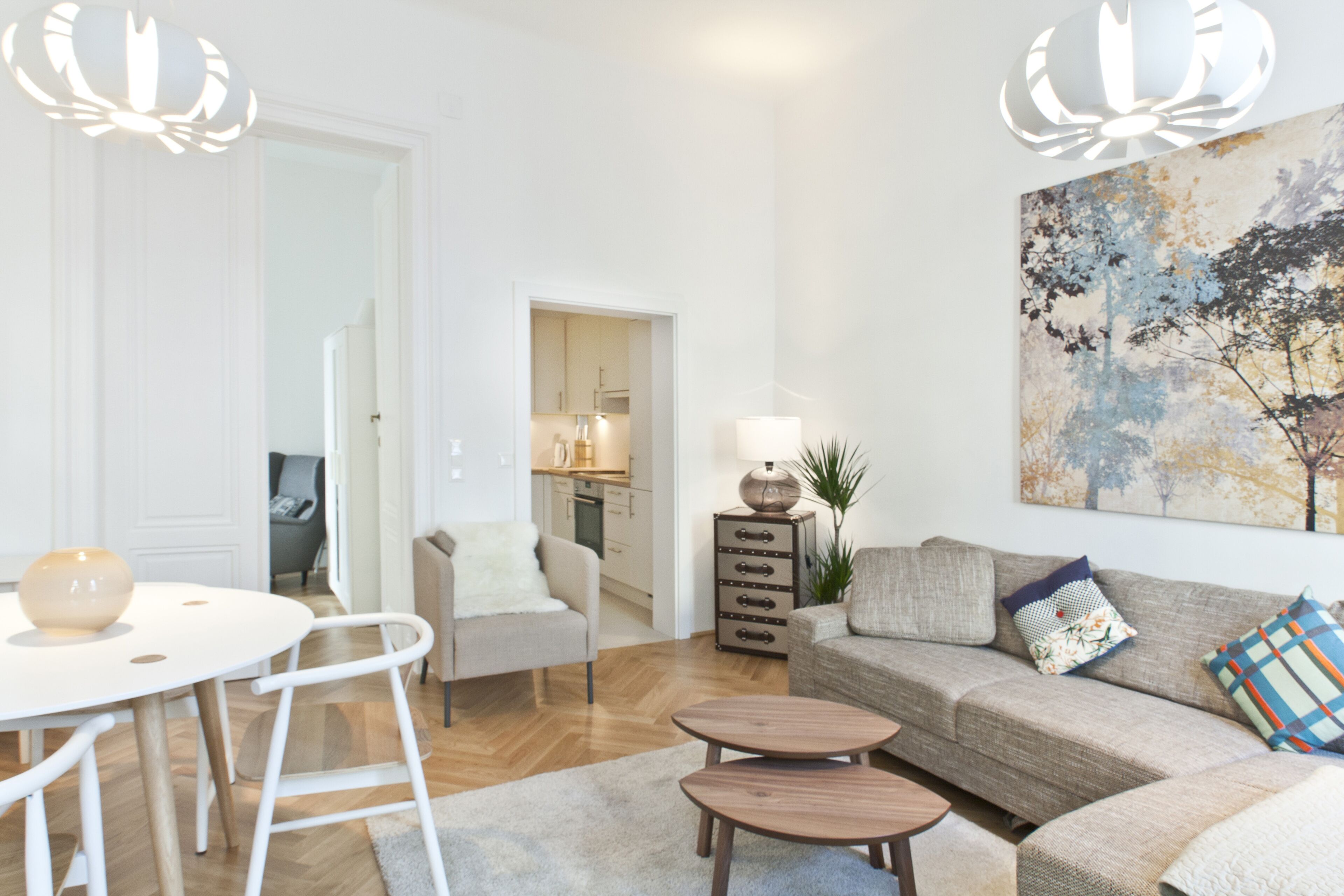 A modern living room with a sofa, coffee table, and a dining area with a table and chairs.