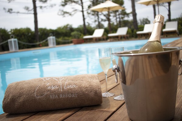 A spa resort pool area with a champagne bottle, glasses, and a towel. - Casa Tua Spa Resort (Porto Recanati)