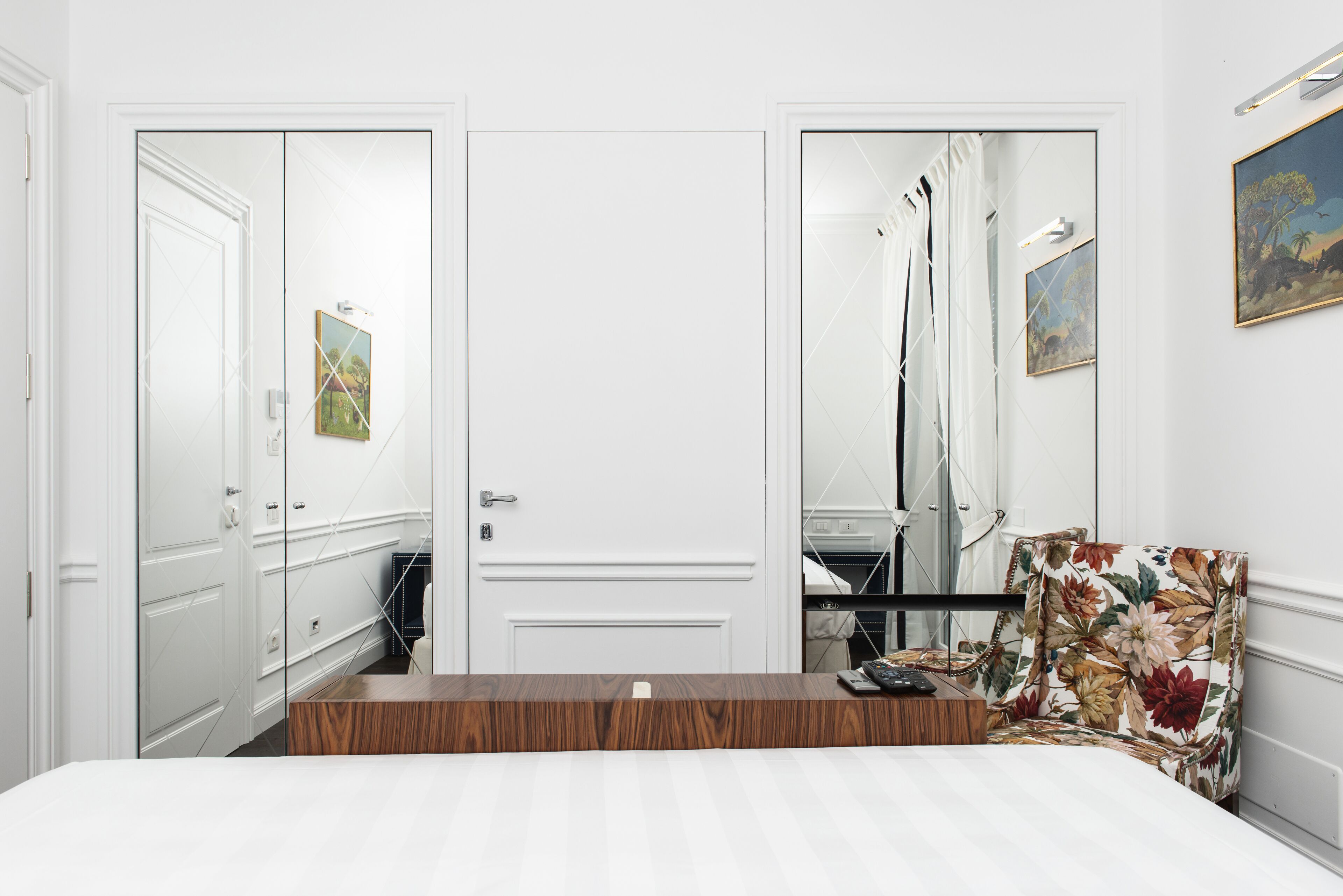A bedroom with a wooden headboard, a bed, a chair, a wardrobe, and a mirror.
