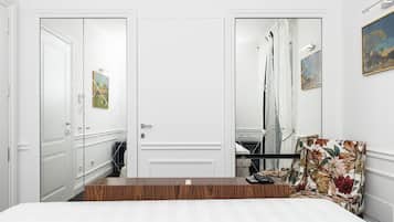 A bedroom with a wooden headboard, a bed, a chair, a wardrobe, and a mirror.
