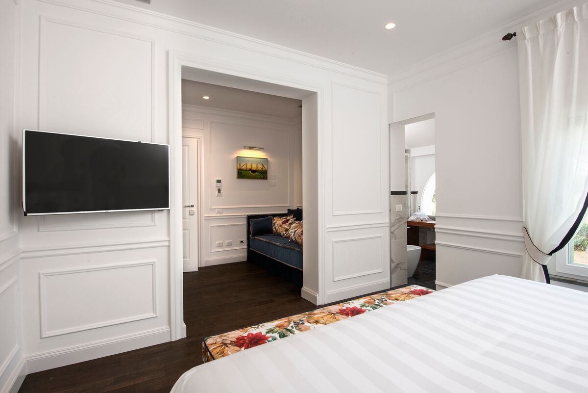 Een hotelkamer met een groot bed, een aan de muur bevestigde televisie, een zithoek met een bank en een stoel, en een klein tafeltje.