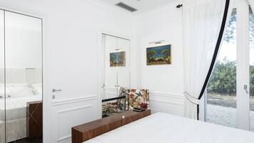 Un dormitorio con una cama grande, una mesita de noche de madera, un espejo y dos cuadros en la pared.