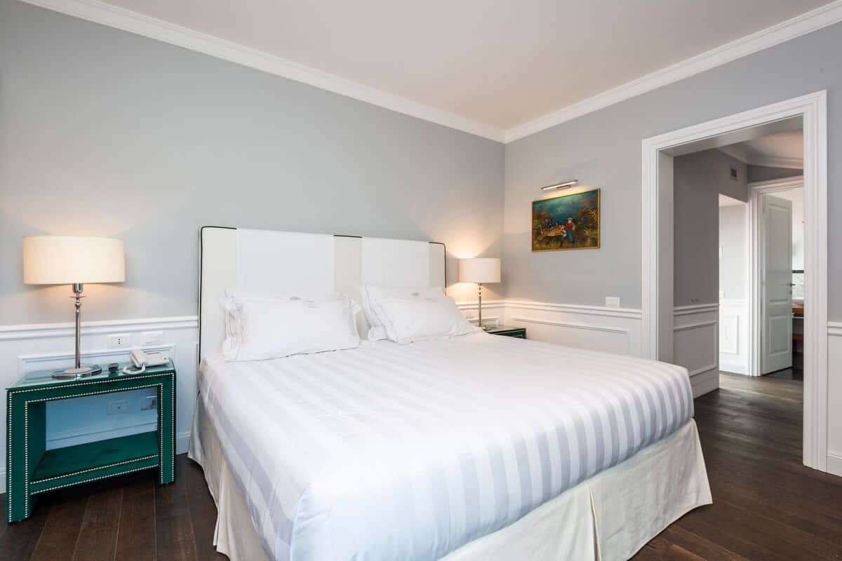 A neatly arranged hotel room with a large bed, two bedside tables with lamps, and a painting on the wall.