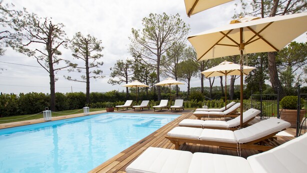 A poolside area with wooden deck, lounge chairs, and umbrellas. - Casa Tua Spa Resort (Porto Recanati)