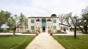 A building with a central entrance, flanked by potted plants and a gravel path leading to the door. - Casa Tua Spa Resort (Porto Recanati)