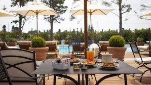 An outdoor dining area with a table set for breakfast, including a pitcher of orange juice, plates of food, and condiments. - Casa Tua Spa Resort (Porto Recanati)