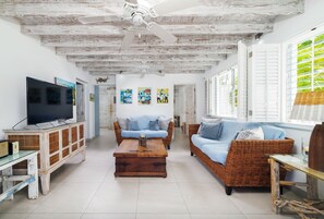 A spacious living room with a television, two sofas, a coffee table, and a ceiling fan.