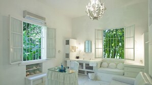 A bright, white bathroom with a vanity, a sink, a mirror, and a bench.