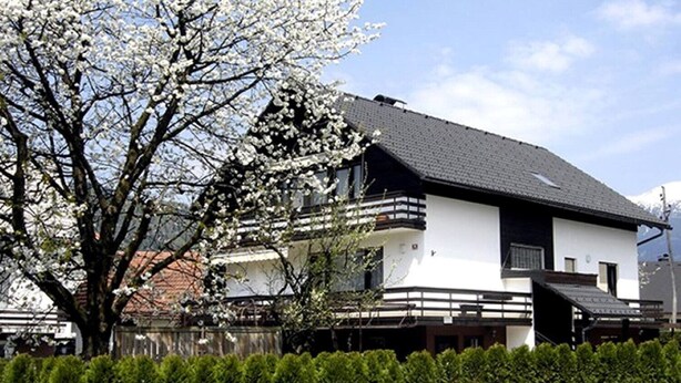 A two-story house with a balcony, surrounded by a well-maintained hedge. - Apartment Lenardic Bled (Bled)